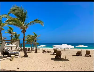 a beach with chairs and umbrellas and the ocean at Apartamento Cómodo en Punta Cana in Punta Cana