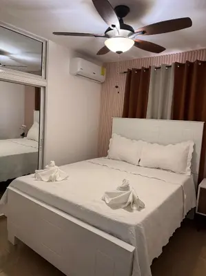 a bedroom with a bed with a ceiling fan and a mirror at Acogedor y céntrico apartamento en Palmas de Gurabo in Santiago de los Caballeros