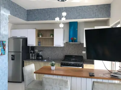 a kitchen with white cabinets and a table with a flat screen tv at Apartamento en Boca Chica T2 501 in Boca Chica