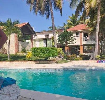 a swimming pool in front of a house with palm trees at Emmanuel villas luxury in Puerto Plata