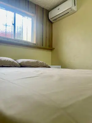 a white bed in a room with a window at La Casita De Chucho in Santiago de los Caballeros