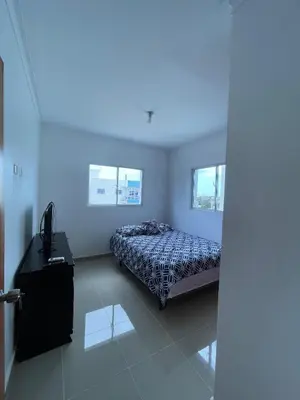 a bedroom with a bed and a desk in it at Comodo apartamento en Boca Chica SDQ AILA in El Higo
