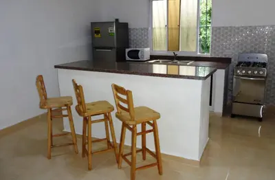 a kitchen with a counter with two chairs and a stove at Aparta hotel El Sol, Home near AirPort SDQ in Boca Chica