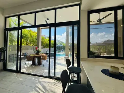 a living room with large windows and a table and chairs at Villa Aguacate Near the Beach in Juan Dolio