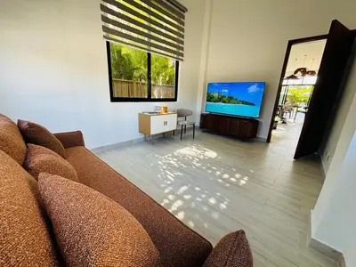 a living room with a couch and a flat screen tv at Villa Aguacate Near the Beach in Juan Dolio