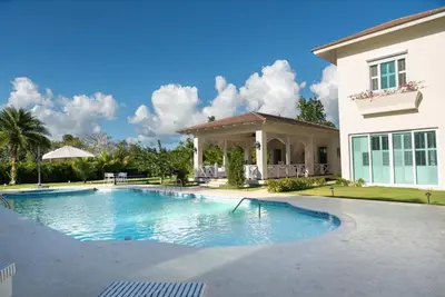 a swimming pool in front of a house at Casa de Campo Luxury Villa with private Pool & Jacuzzi, Near Beach, Marina, Golf, Restaurants & Altos de Chavon in La Romana