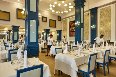 a dining room with white tables and blue chairs at Riu Palace Punta Cana - All Inclusive in Punta Cana