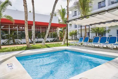 a swimming pool at a resort with chairs and palm trees at Riu Bambu - All Inclusive in Punta Cana