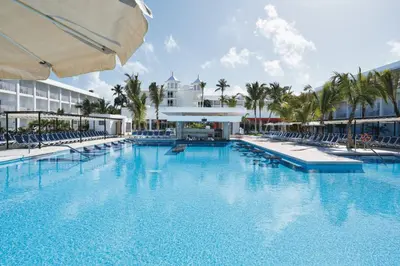 a large swimming pool with chairs and a building at Riu Bambu - All Inclusive in Punta Cana