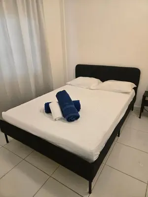 a bed with white sheets and blue towels on it at Hostel capicua in Punta Cana