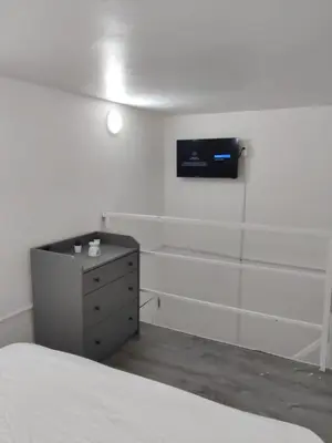 a bedroom with a bed and a dresser with a tv on the wall at Hostel capicua in Punta Cana