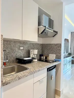 a kitchen with white cabinets and a stainless steel sink at Stylish Studio Samaná Bay View, Pool and Gym Access in Santa Bárbara de Samaná
