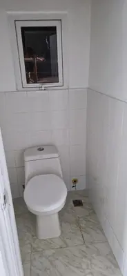 a white bathroom with a toilet and a window at Casa Perez CCC in Juan Dolio