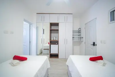 two beds in a white room with red pillows at Le Camere Del Maestro in Bayahibe
