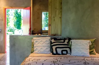 a bedroom with a bed with pillows and a mirror at REFUGIO Sabaneta de Yasica in Cabarete