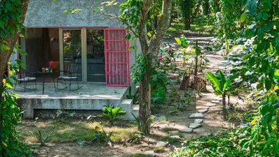 a small house with a red door in a garden at REFUGIO Sabaneta de Yasica in Cabarete