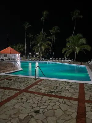 a swimming pool at night with chairs and palm trees at Vista palmera in Juan Pedro