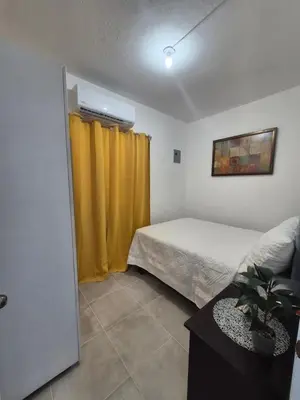 a bedroom with a bed and a yellow curtain at OMY Apartments Nagua 2A in Nagua