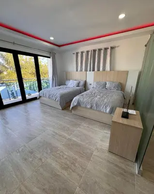 a bedroom with two beds and a table and windows at villas el guano in Sosúa