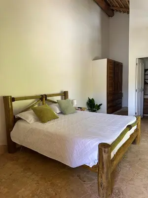a bedroom with a wooden bed with white sheets and green pillows at Guest-Room 1 Palmeras - 3 Pax, 5 Min de La Playa in Las Galeras