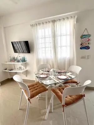 a white dining room with a glass table and chairs at Apartamento a solo pasos del centro y la playa in Bayahibe