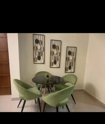 a dining room with a table and green chairs at Leni's Confort in Santiago de los Caballeros