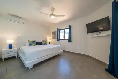 a bedroom with a white bed and a flat screen tv at Location , Vibe , Style in Sosúa
