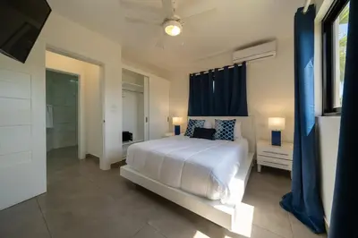 a bedroom with a white bed and a blue curtain at Location , Vibe , Style in Sosúa