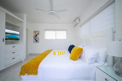 a white bedroom with a white bed with yellow pillows at Luxury Villa, Garden View and Private Pool in La Mulata