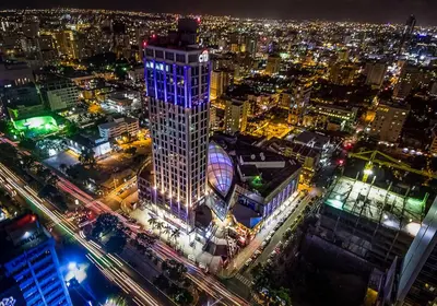 a city lit up at night with a tall building at Apartamento céntrico 1BR Piantini in Santo Domingo