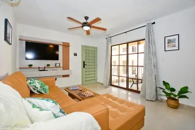 a living room with a couch and a flat screen tv at Tropical Retreat in El Cortecito beach condo in Punta Cana