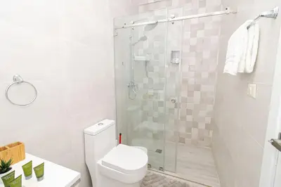 a white bathroom with a shower and a toilet at Bright 2BR Apartment with Pool near Bayahibe Beach in San Rafael del Yuma