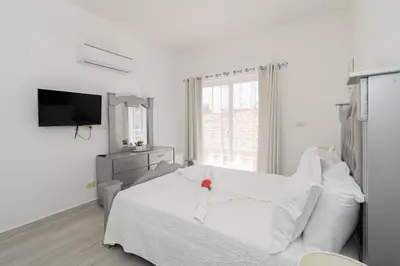 a white bedroom with a bed and a television at Bright 2BR Apartment with Pool near Bayahibe Beach in San Rafael del Yuma