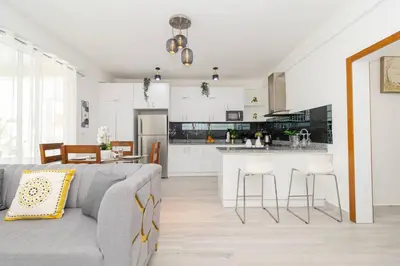 a living room with a gray couch and a kitchen at Bright 2BR Apartment with Pool near Bayahibe Beach in San Rafael del Yuma