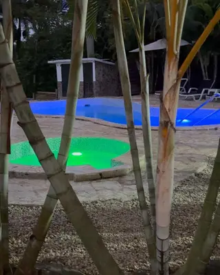 a pool with a green light in front of some trees at Colina Buena Vista VIP in Jarabacoa