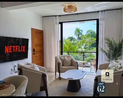 a living room with chairs and a table and a balcony at Brand New Condo-Sunrise in Puerto Plata