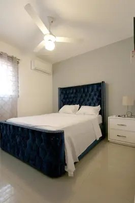 a bedroom with a large bed with a blue headboard at Lujoso Pent-house en el Residencial Mediterráneo in Santiago de los Caballeros