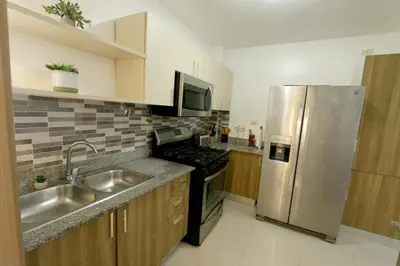 a kitchen with a stainless steel refrigerator and a sink at Lujoso Pent-house en el Residencial Mediterráneo in Santiago de los Caballeros