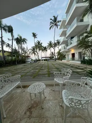 a patio with chairs and tables in front of a building at Apartamento frente a la playa in Punta Cana