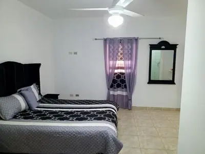 two beds in a room with a mirror and purple curtains at Home away from home in Guayacanes