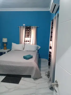 a bedroom with a bed with a blue wall at Home away from home in Guayacanes