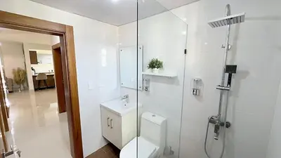 a white bathroom with a toilet and a shower at Luxury Apartment-PRIVATE Patio & BBQ-Near Airport in Santiago de los Caballeros