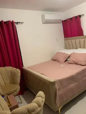 a bed and a chair in a room with red curtains at Residencial habitat uno in Los Paredones