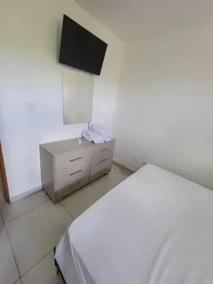 a bedroom with a bed and a tv on the wall at Palma Real Apt Near Cibao Airport & Pool in Santiago de los Caballeros