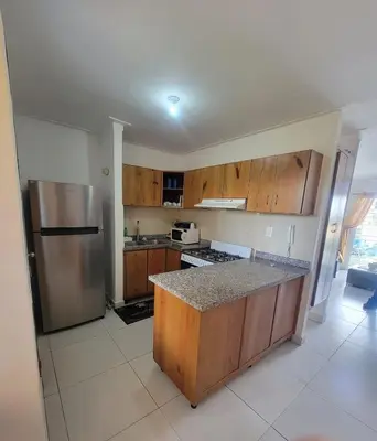 a kitchen with wooden cabinets and a stainless steel refrigerator at Palma Real Apt Near Cibao Airport & Pool in Santiago de los Caballeros