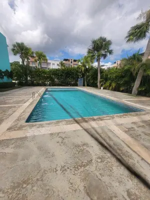 a swimming pool with palm trees and a building at Palma Real Apt Near Cibao Airport & Pool in Santiago de los Caballeros