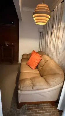 a couch with an orange pillow on it in a room at Cozy and Beautiful, 3 Bedroom Apartment Home in Santo Domingo