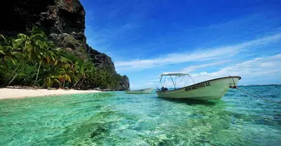 a boat in the water next to a beach at Villas Reynoso, Near La Playita Beach in Las Galeras Samaná in Las Galeras