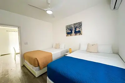 two beds in a white room with a blue blanket at Condominio privado con piscina, cerca de la playa in Punta Cana