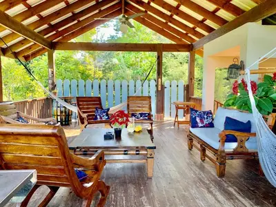 a porch with rocking chairs and a hammock at Villa del Pino en Quintas del Bosque in Jarabacoa